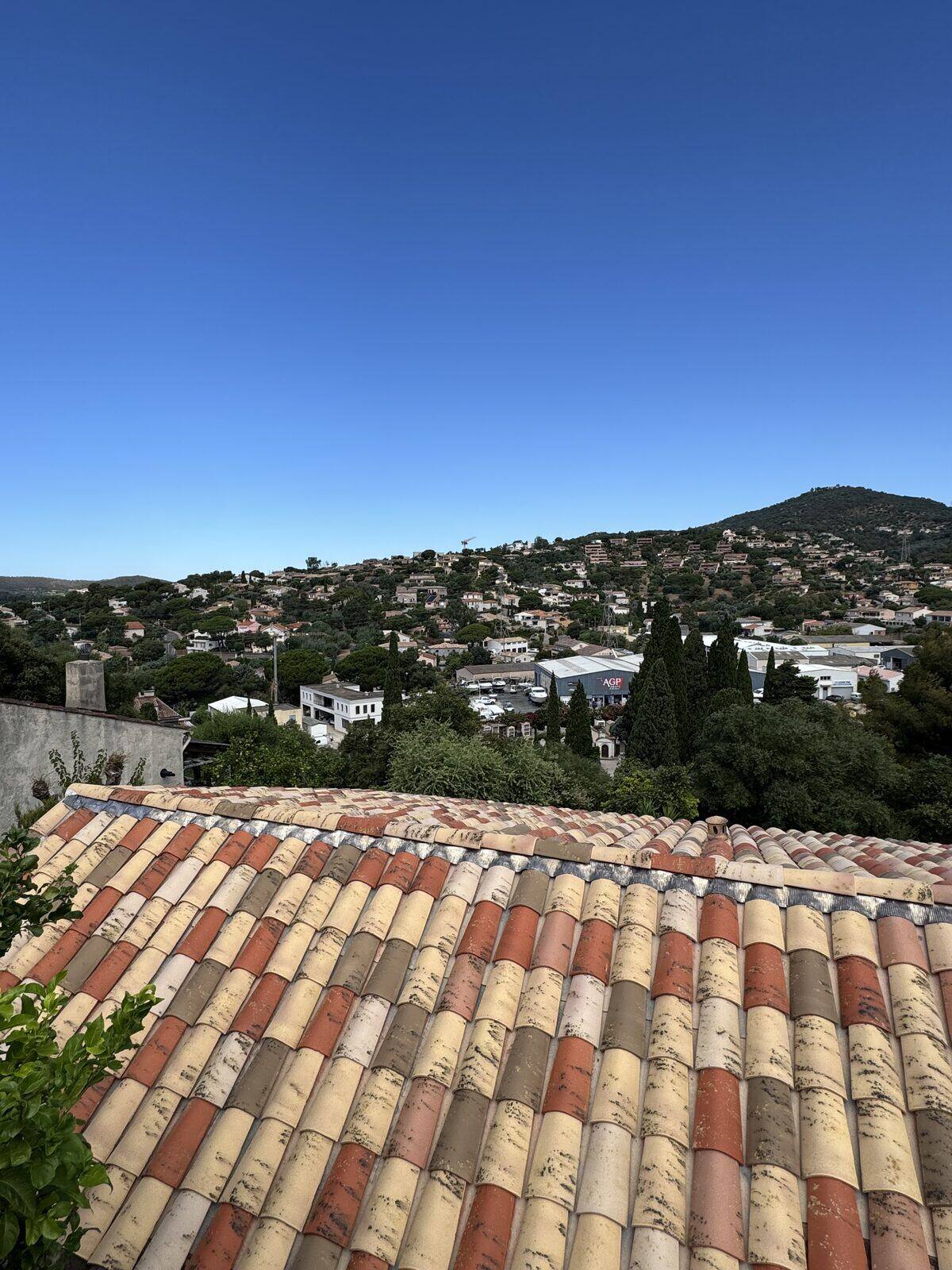 Toiture rénovée en tuiles panachées dominant un village du Var